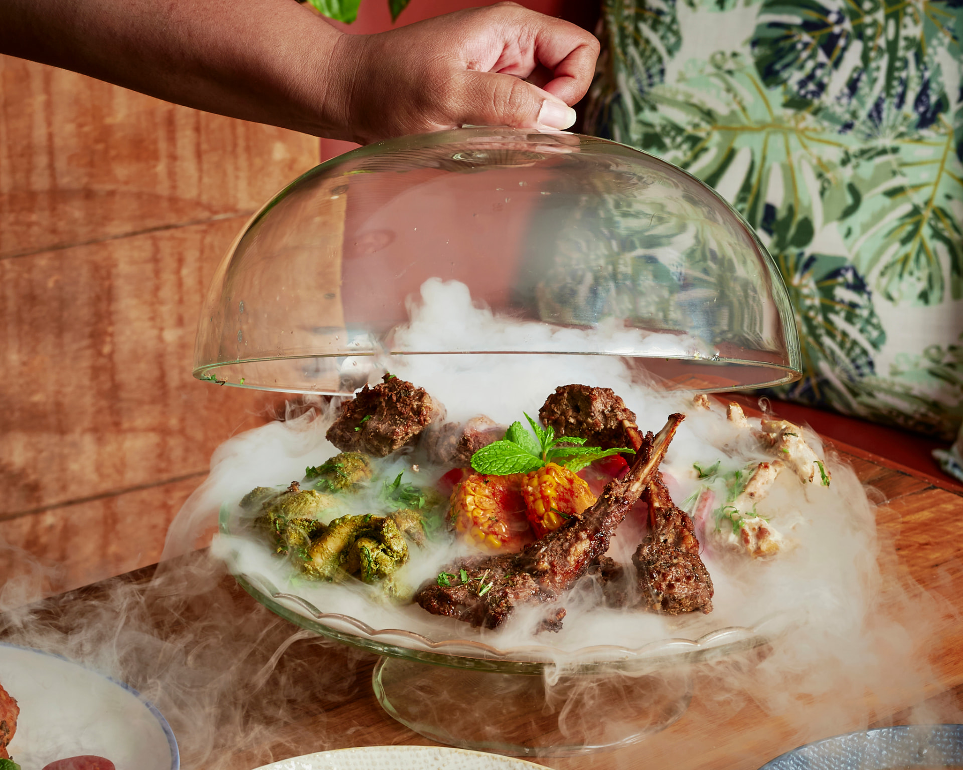 Original photograph of the Smoked Platter — mixed grill kebabs and corn on a glass platter as a smoke-filled glass dome is lifted away