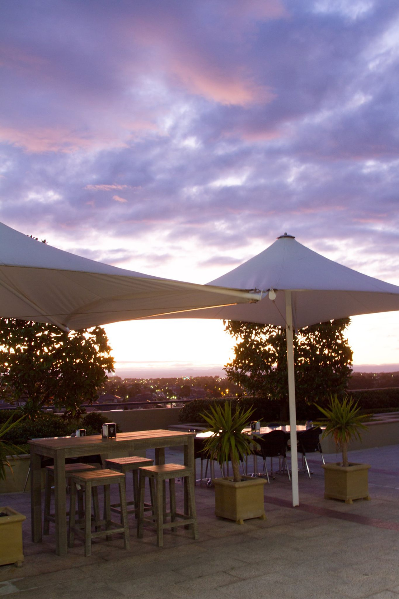 Golden light on high bar stools under terrace umbrellas