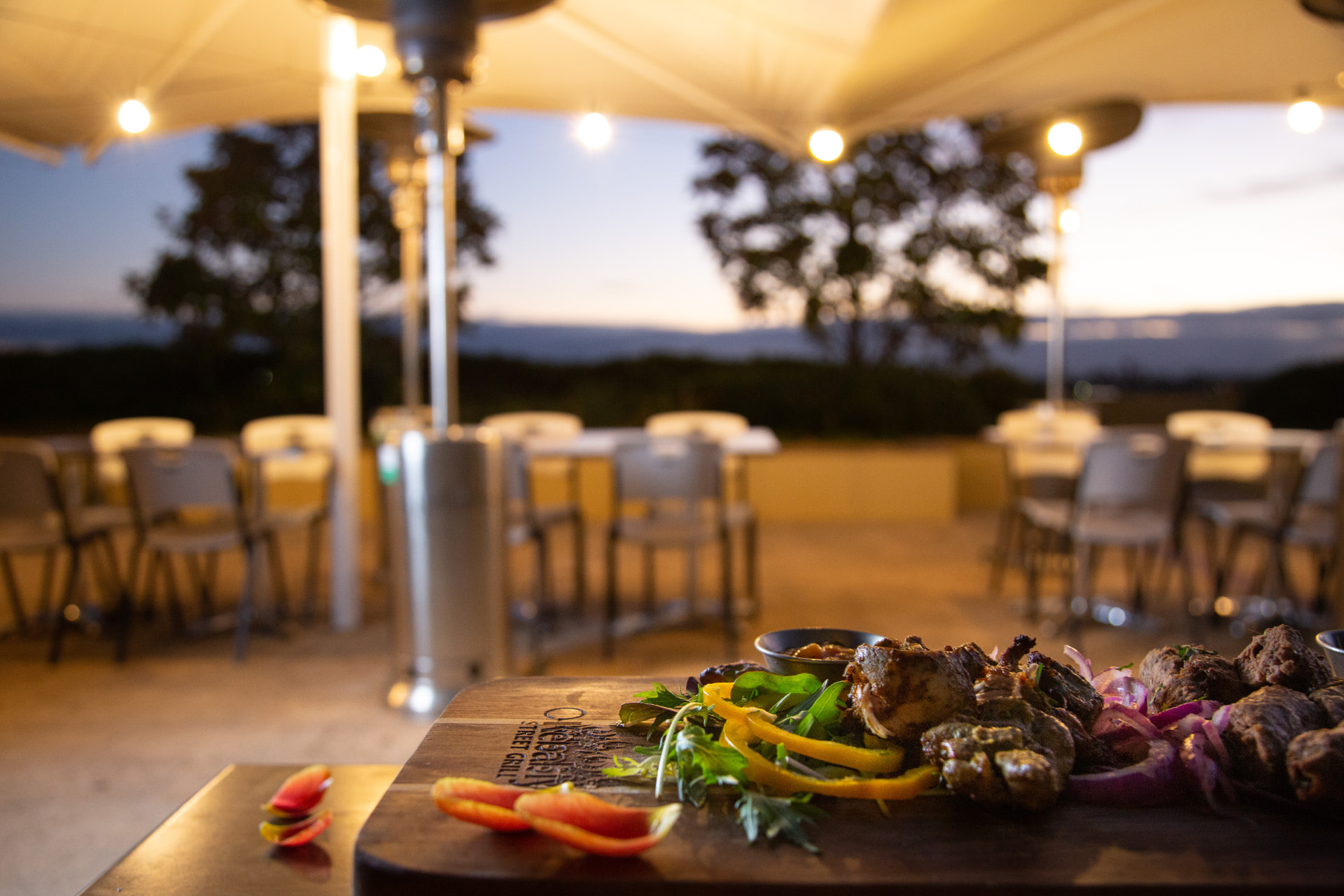 Grilled kebabs under terrace umbrellas at dusk
