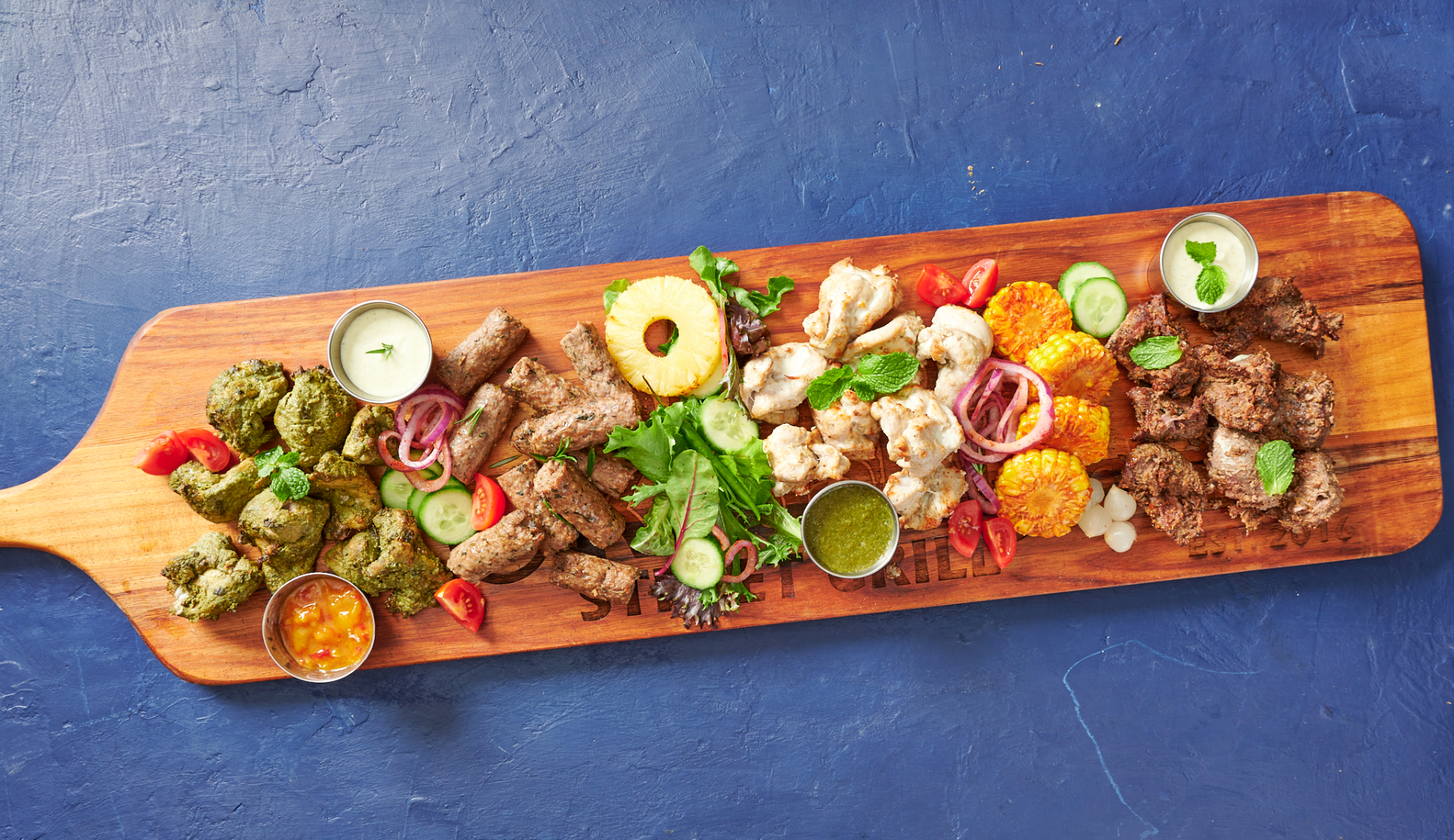 Metre-long rustic wooden platter overflowing with kebabs, biryani and chutneys