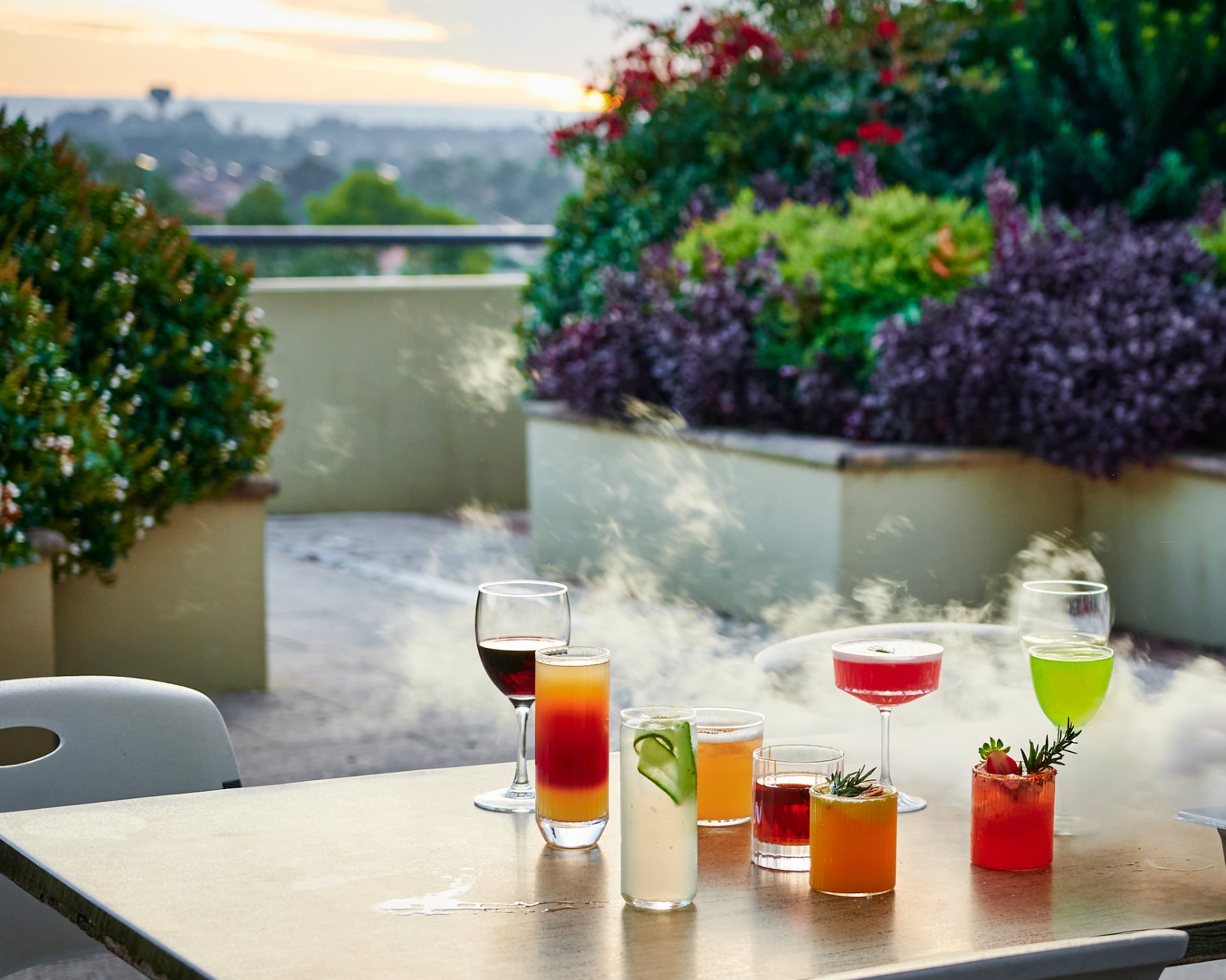 Sharabiya kocktails and mocktails lined up on a terrace table at sunset over the Hills District